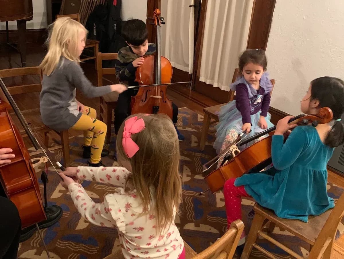Children playing string instruments together indoors.