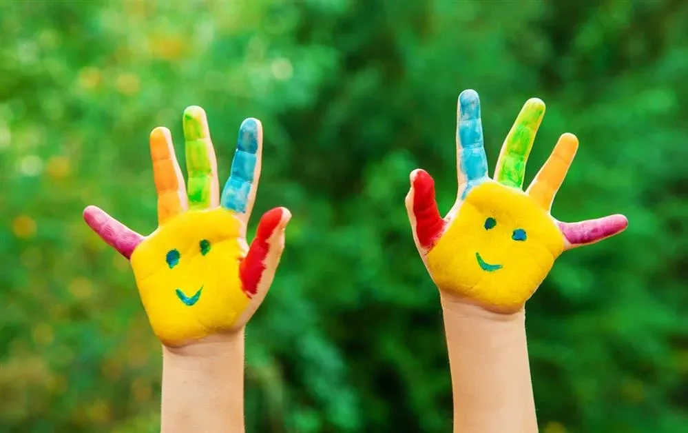 A pair of child's hands painted in yellow with smiley faces. — provider photo from Missoula TEACH Academy