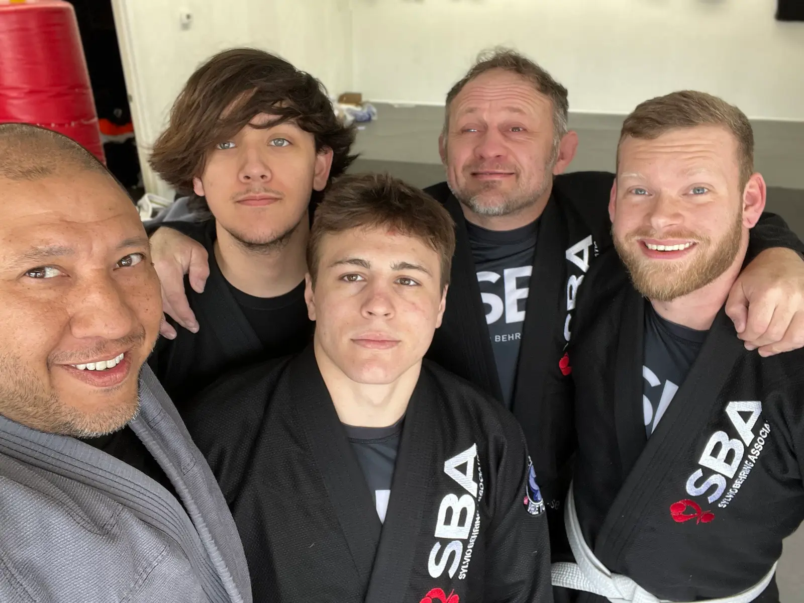 A group of five men wearing martial arts uniforms pose for a photo.
