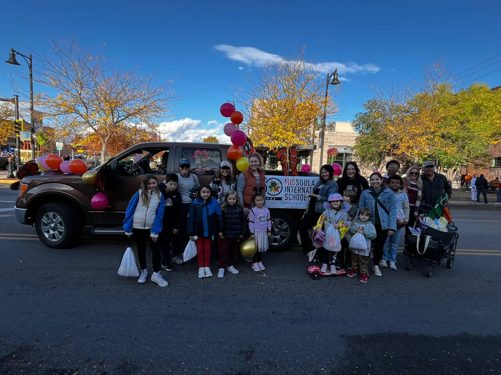 A group of children and adults pose in front of a decorated truck during an outdoor event.