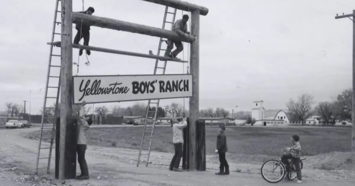 Men install a sign reading "Yellowstone BOYS' RANCH" while others watch nearby.