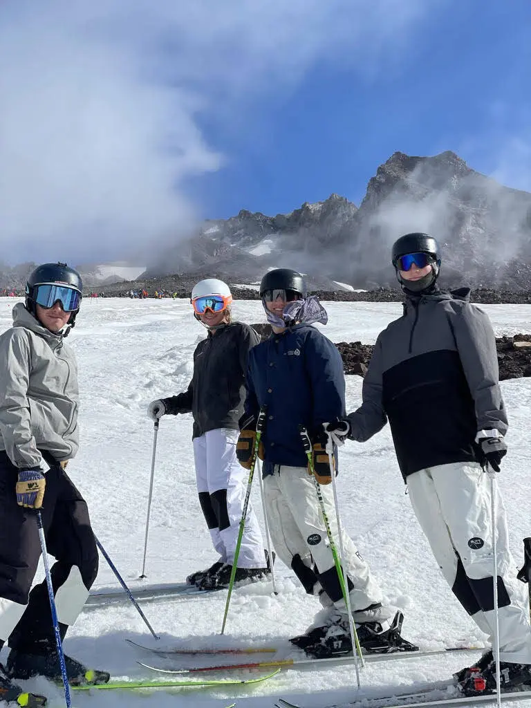 Four people in ski gear stand together on a snowy mountain.