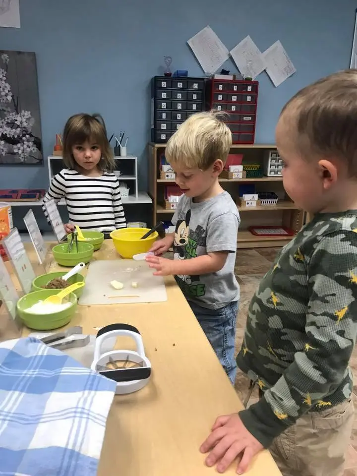 Three children are preparing food during a classroom activity.