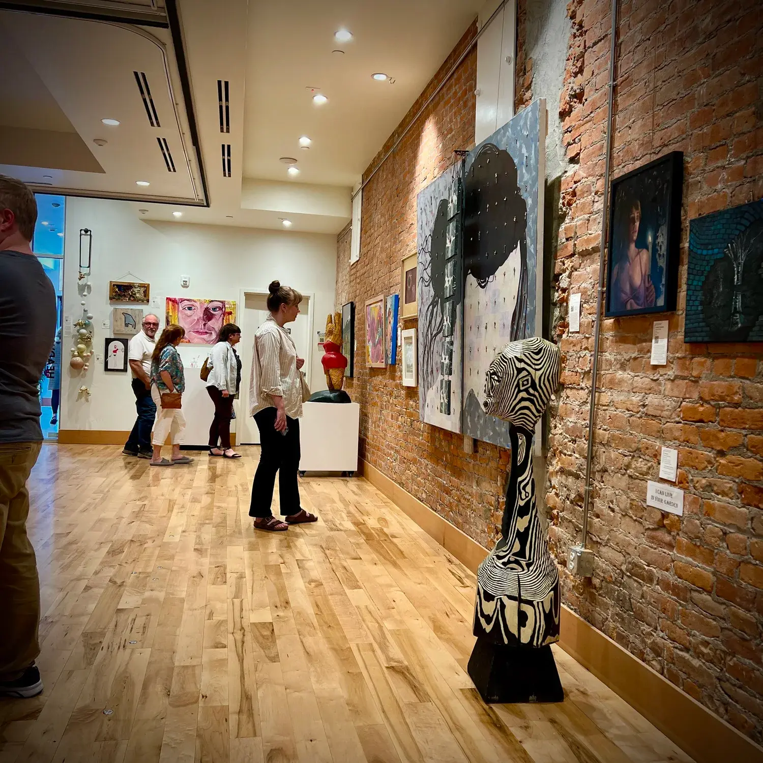 Visitors observe artwork displayed in an art gallery.