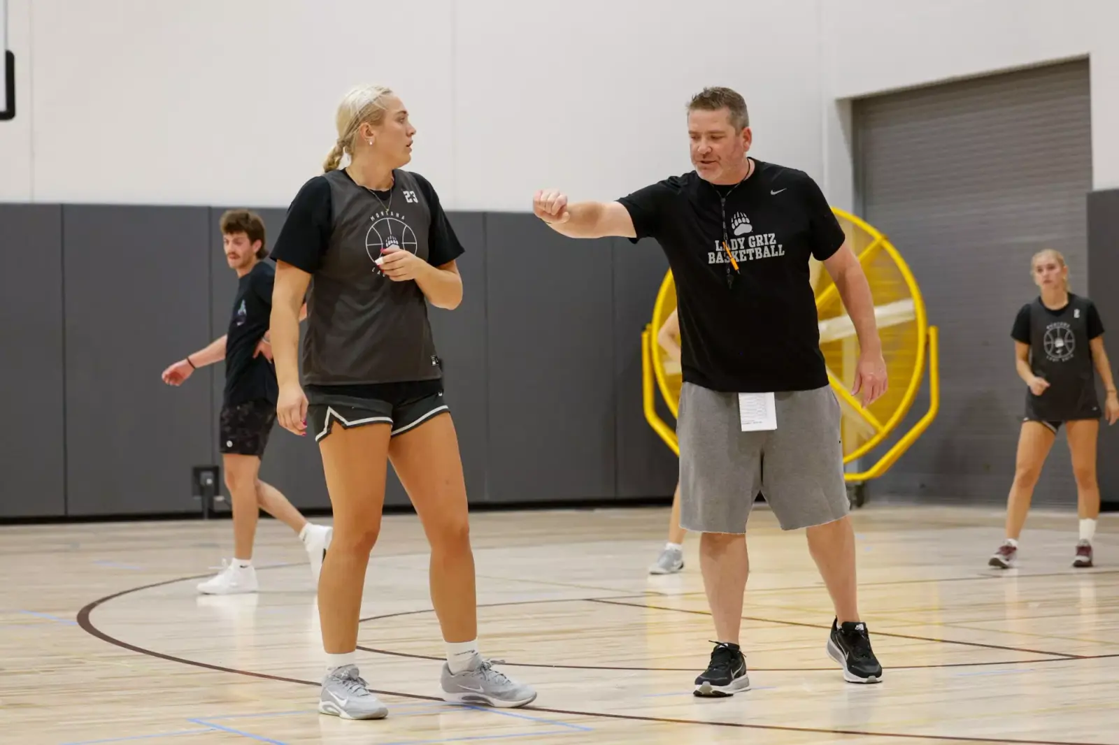 A basketball coach gives a fist bump to a player on a court.