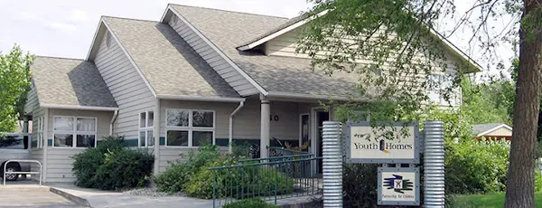 A view of the exterior of a building with a sign identifying it as Youth Homes.