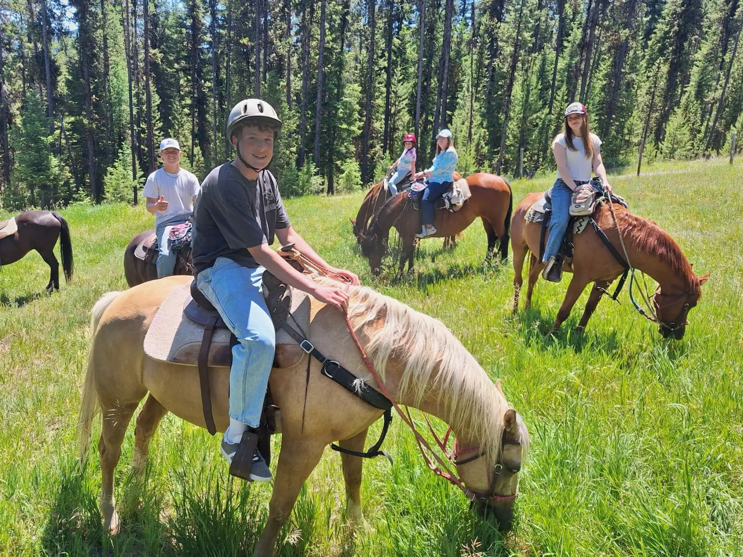 A group of people ride horses through a grassy field.
