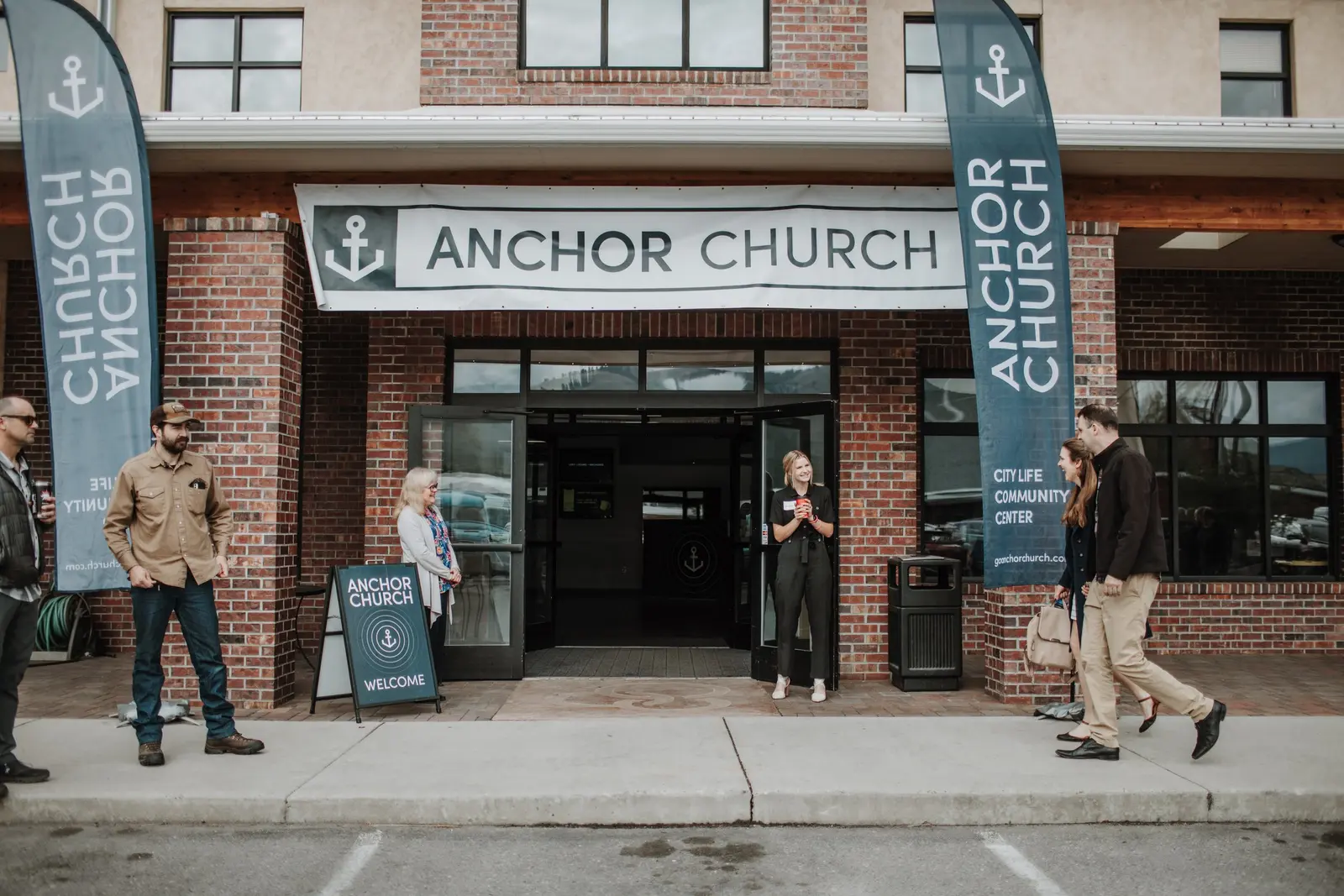 People stand outside the entrance to a building marked with church signage.