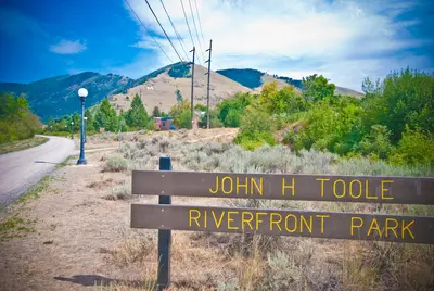 Photo from ci.missoula.mt.us A sign marks the entrance to a park with a mountain in the background.