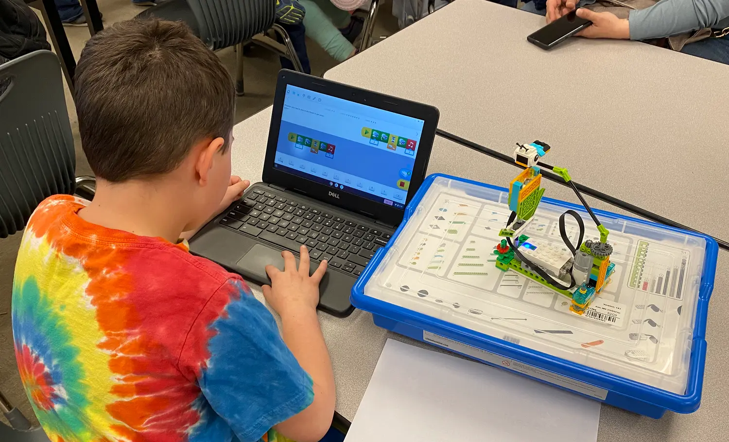 A child uses a laptop to program a robotic construction kit on a table.