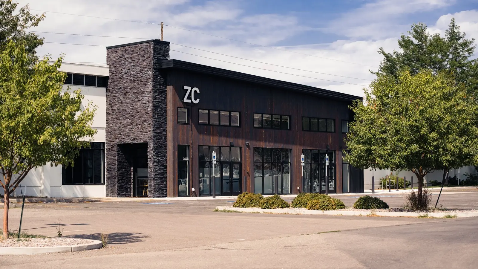 A modern commercial building with stone and wood siding is situated next to a parking lot.