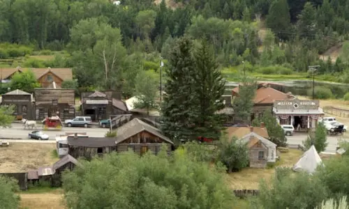 A view of a historic-style western town with wooden buildings and a teepee.
