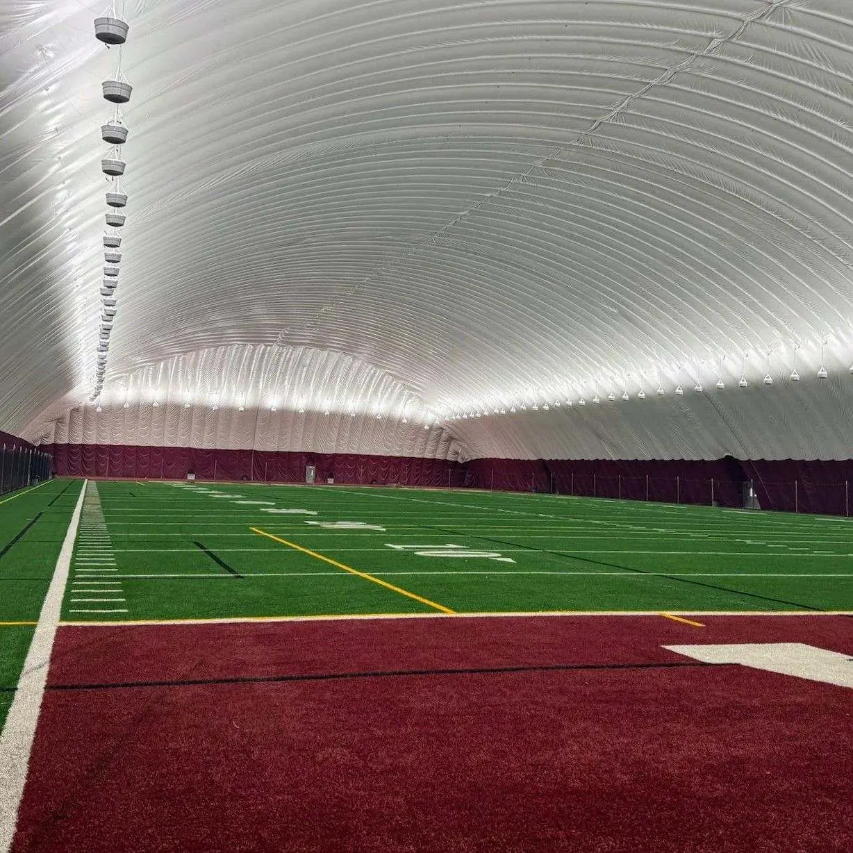 An indoor athletic field is shown inside a large dome structure.