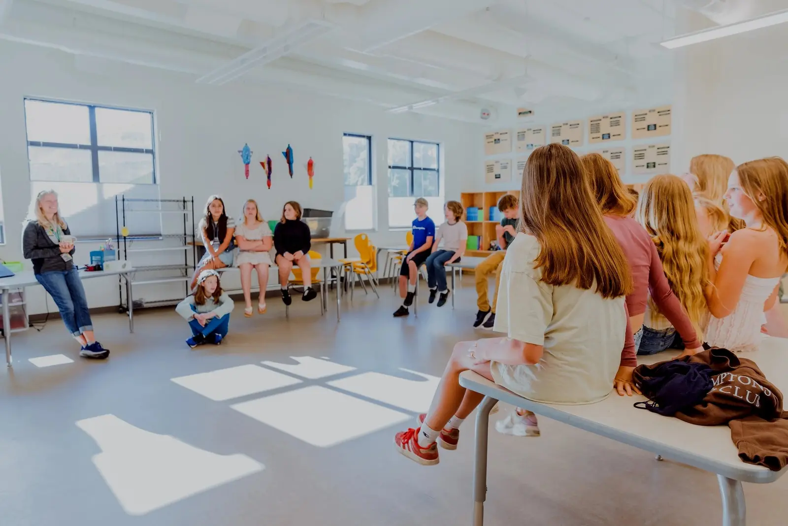 A teacher leads a group of children sitting in a classroom.