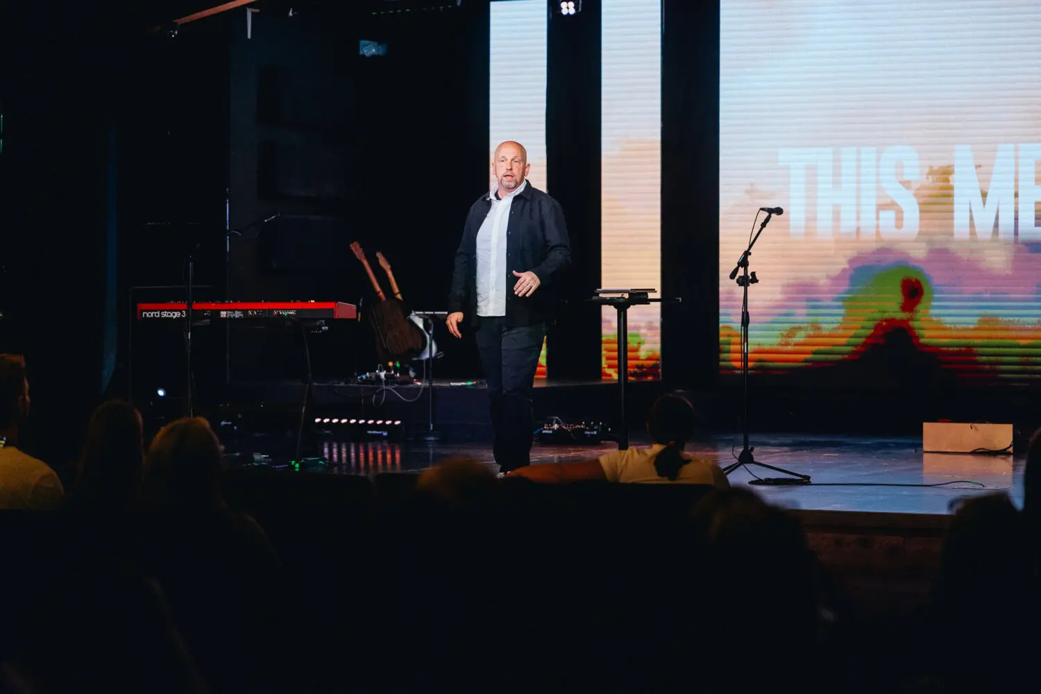 A man stands on a stage addressing an audience.