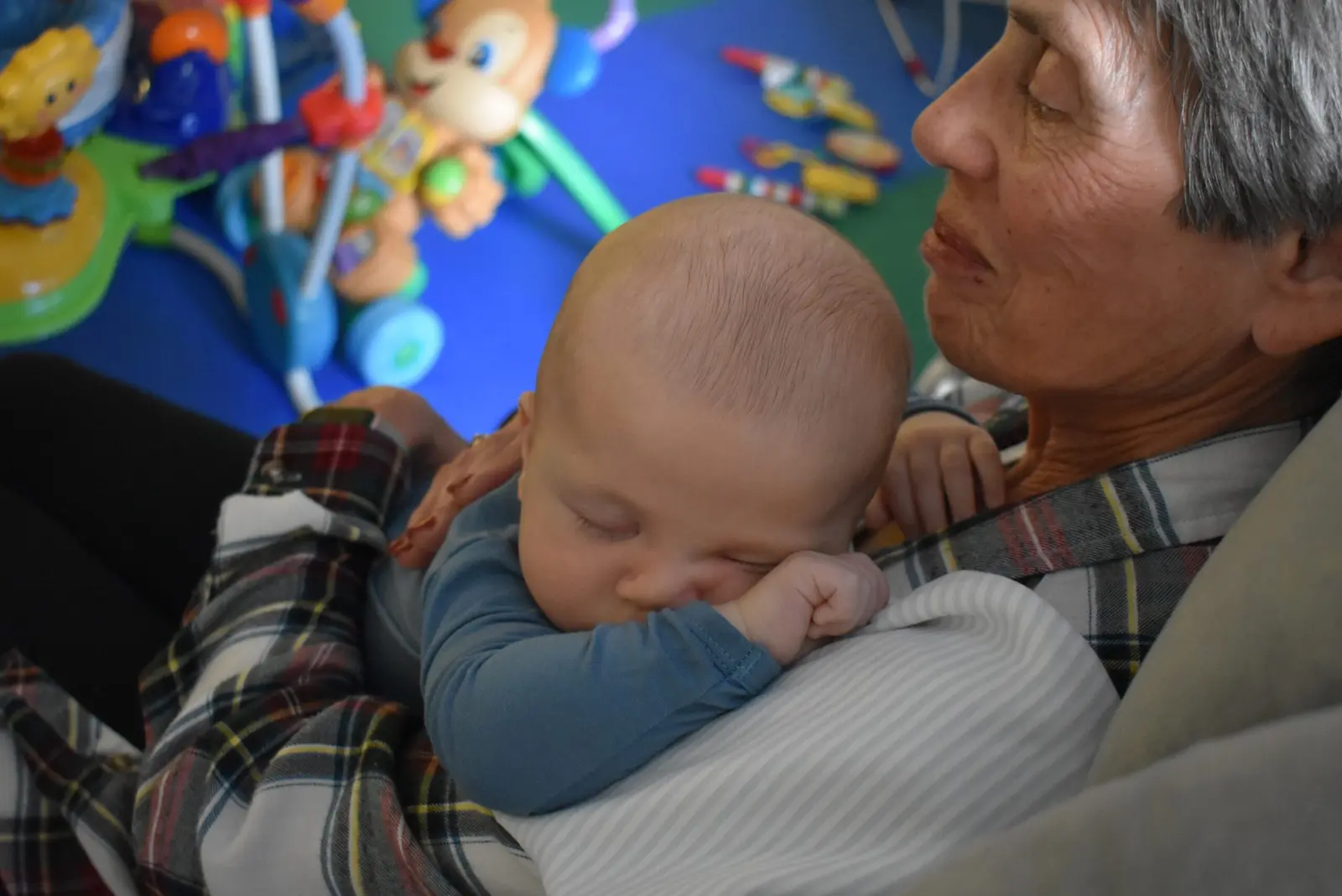 An adult holds a sleeping infant against their shoulder.