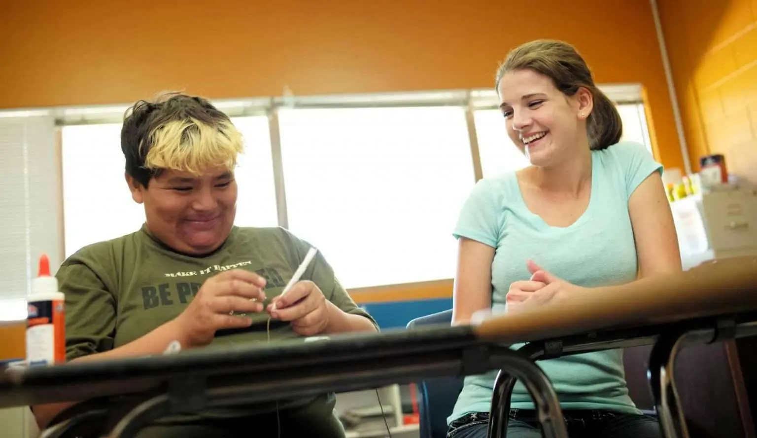 A student and an instructor are working on a project together at a desk.