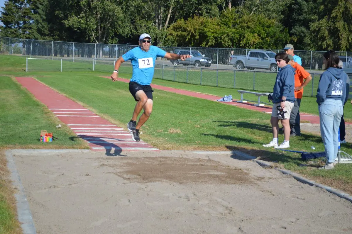 A man competes in a long jump event at an outdoor track.