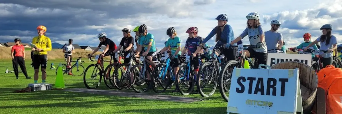 A group of young cyclists prepare for a race at the starting line.