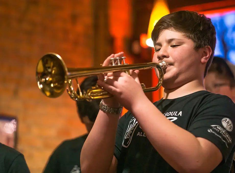 A young boy plays a trumpet during a musical performance.