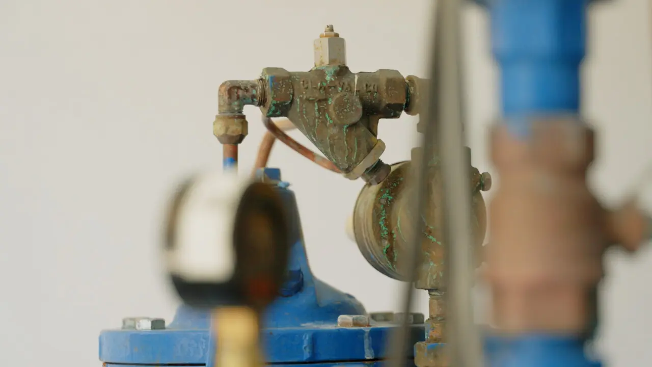A close-up view of a weathered industrial valve and pipe fitting.