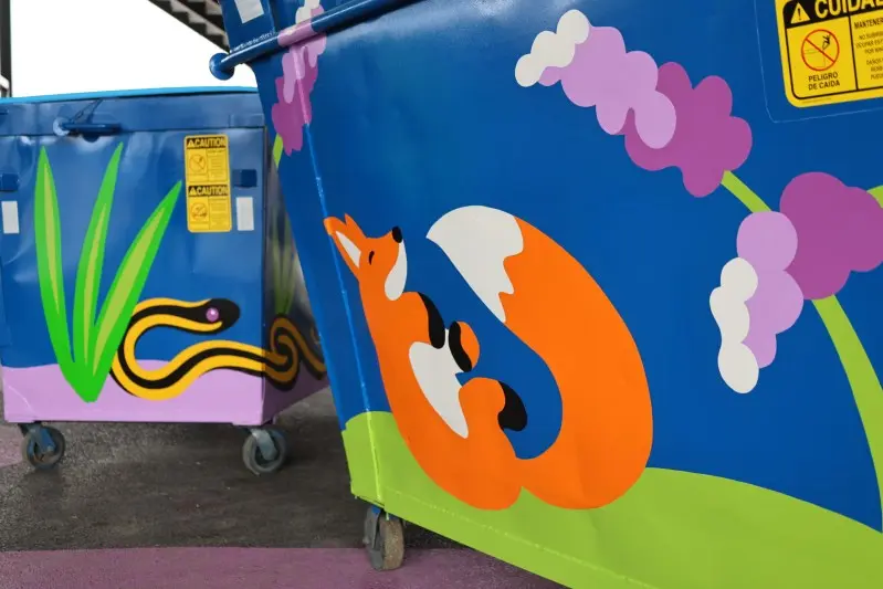 Two blue metal waste bins are painted with colorful nature-themed murals including a fox and a snake.