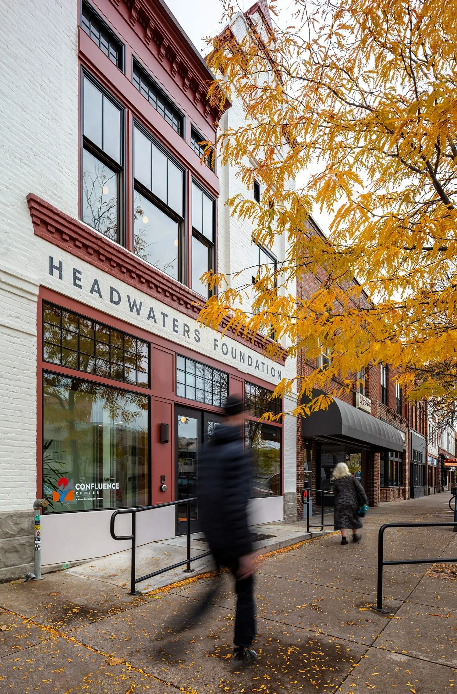 A street-level view of the Headwaters Foundation building with a blurred person walking in the foreground.