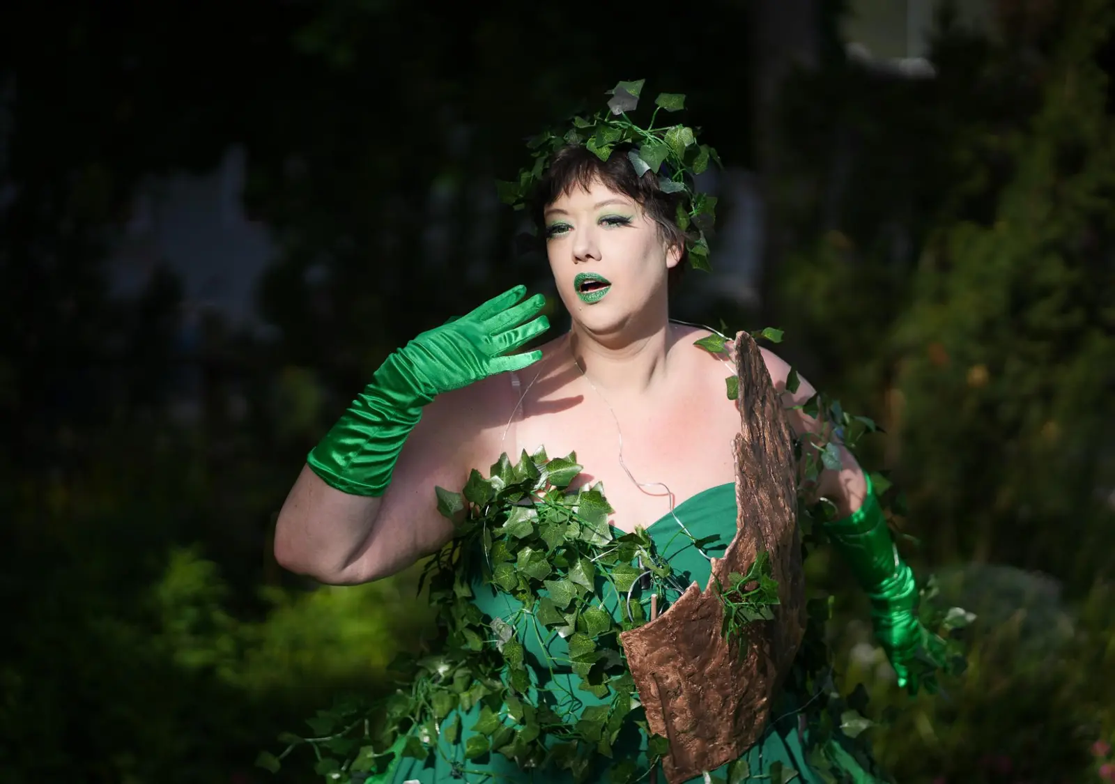 A person dressed in a green vine and leaf costume poses outdoors.