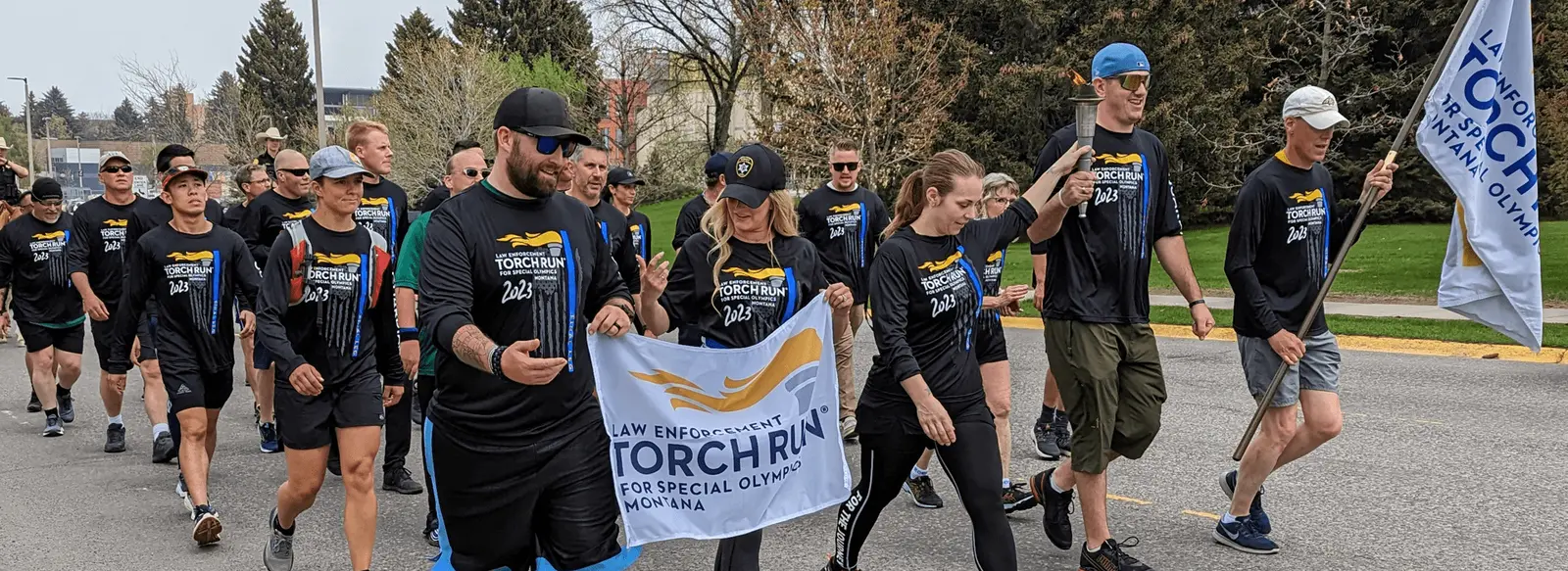 A group of people wearing matching shirts participate in a law enforcement torch run event.