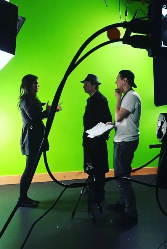 A group of people standing in front of a green screen.