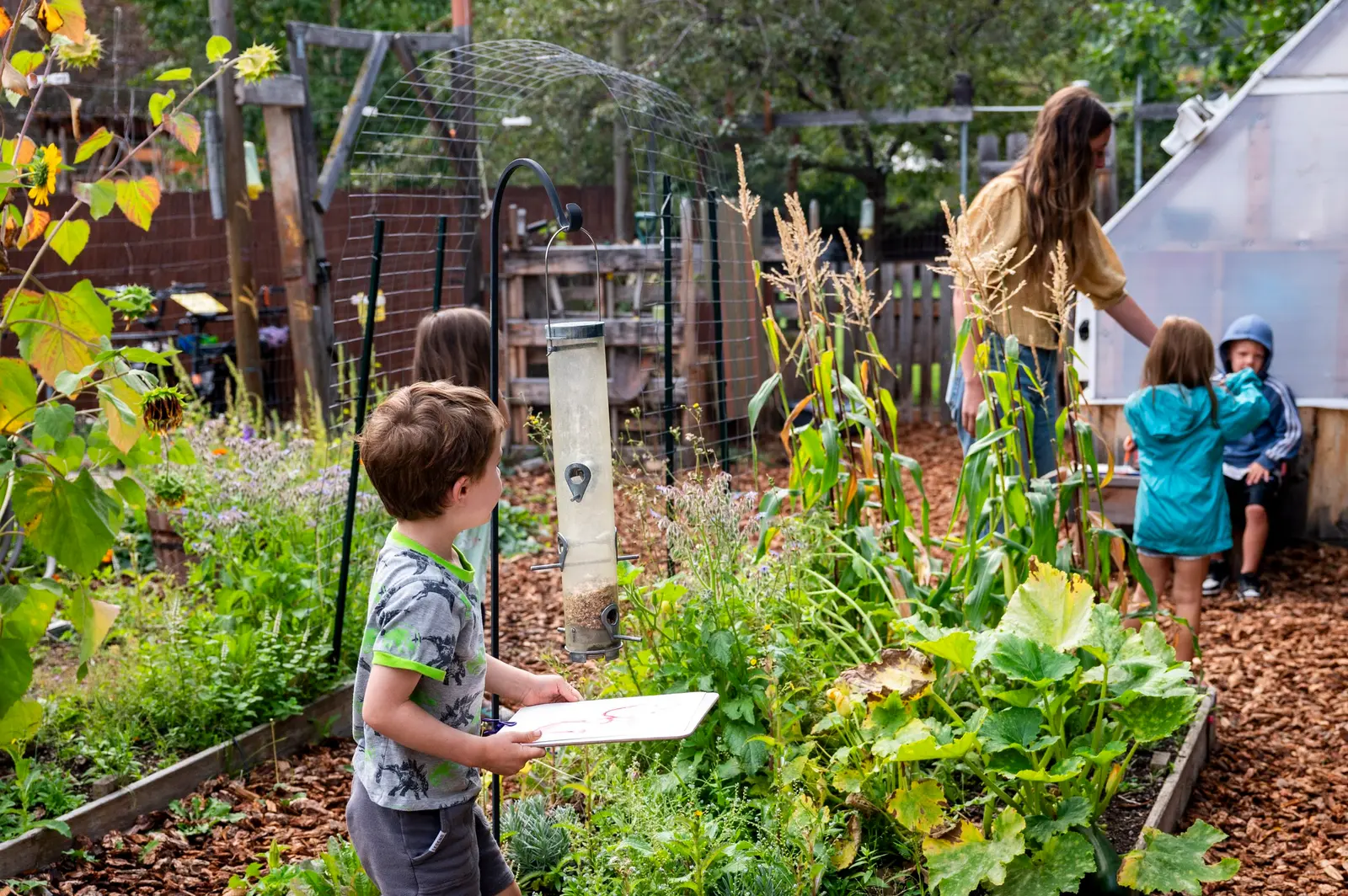 An instructor and children explore a garden area.