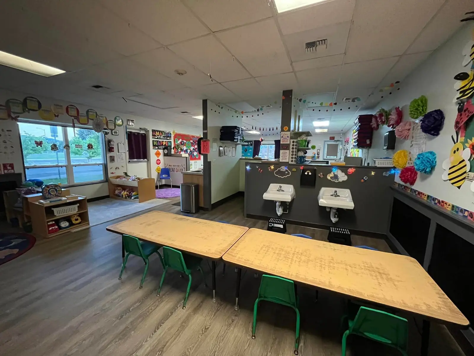 A view of a classroom for young children with small tables and sinks.