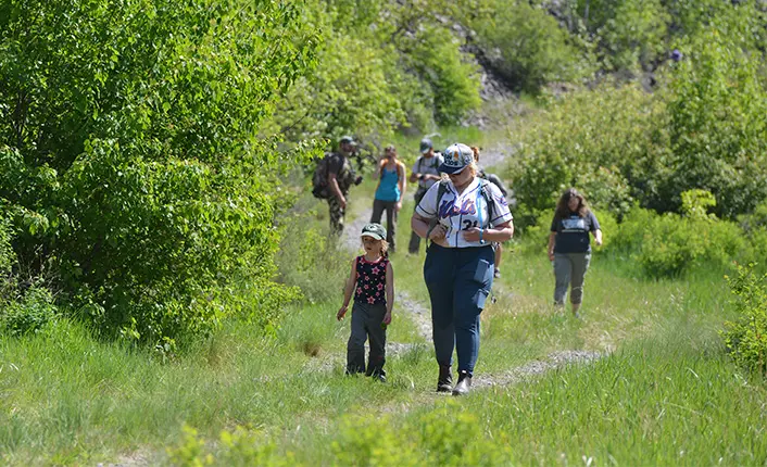 A group of people walk along a grassy trail.