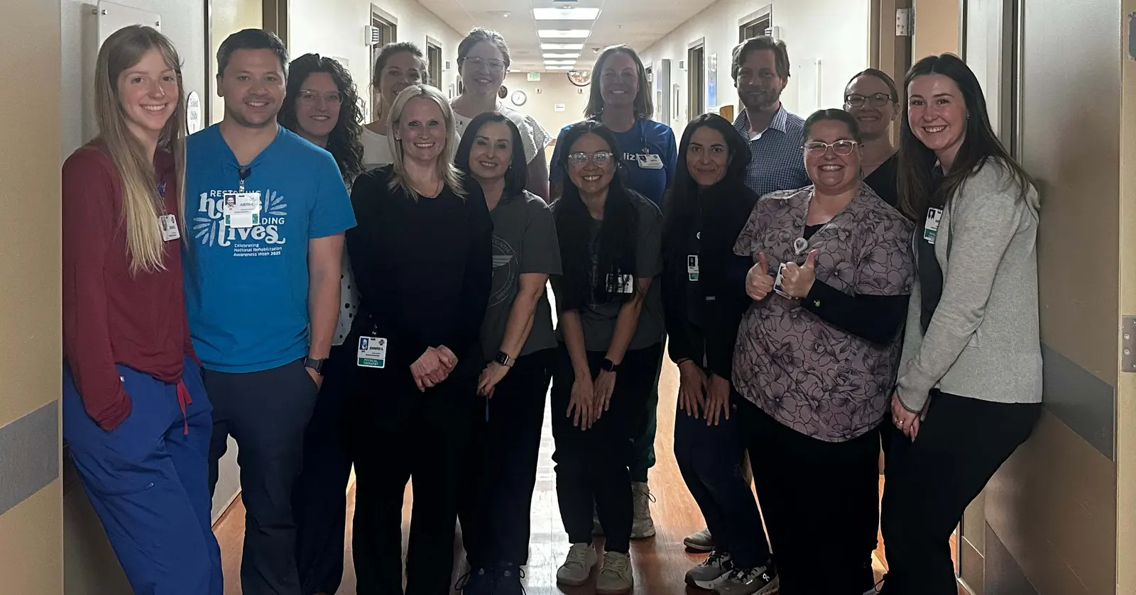 A group of professionals stands together in a hospital or clinic hallway.