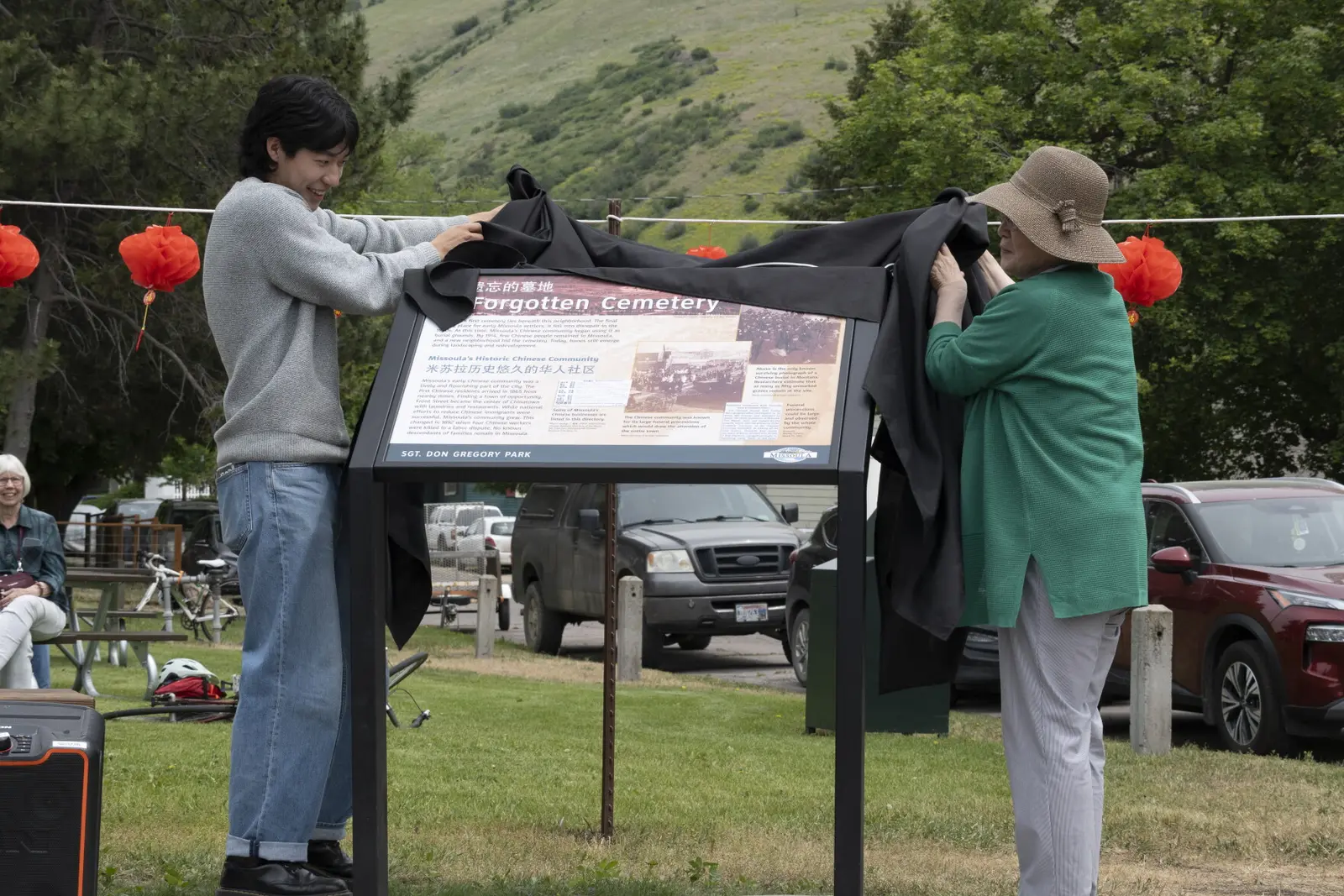 Kim and his grandmother, who made the trip from Seoul, South Korea, lift the cover from the newly installed plaque in Missoula’s Gregory Park on June 6.