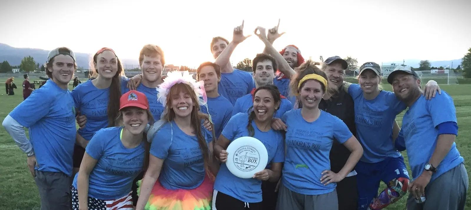 A group of people wearing matching blue t-shirts pose together on a grass field.