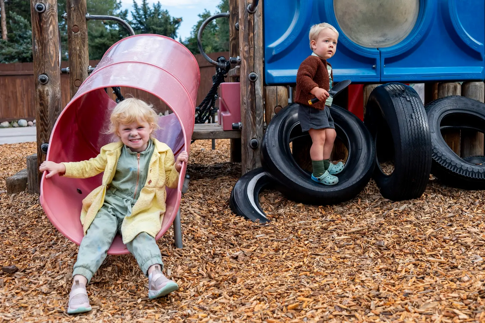 Two children are playing on an outdoor playground structure.