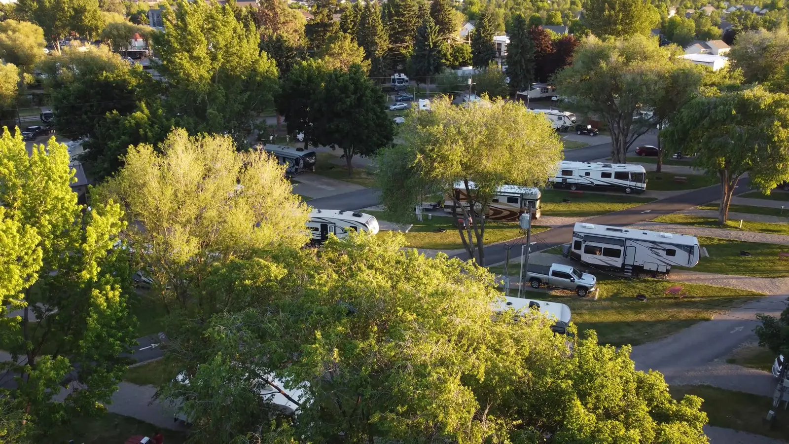 An aerial view shows several recreational vehicles parked in a tree-filled campground.