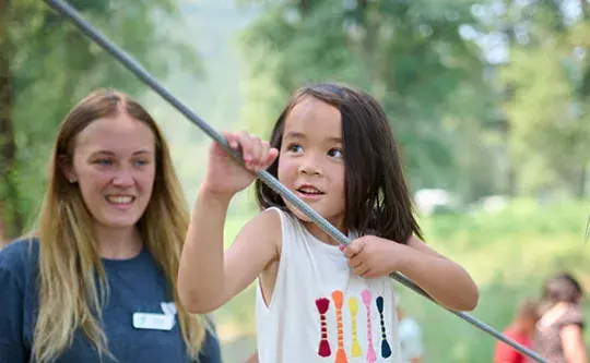 An instructor watches a child participating in an outdoor activity.