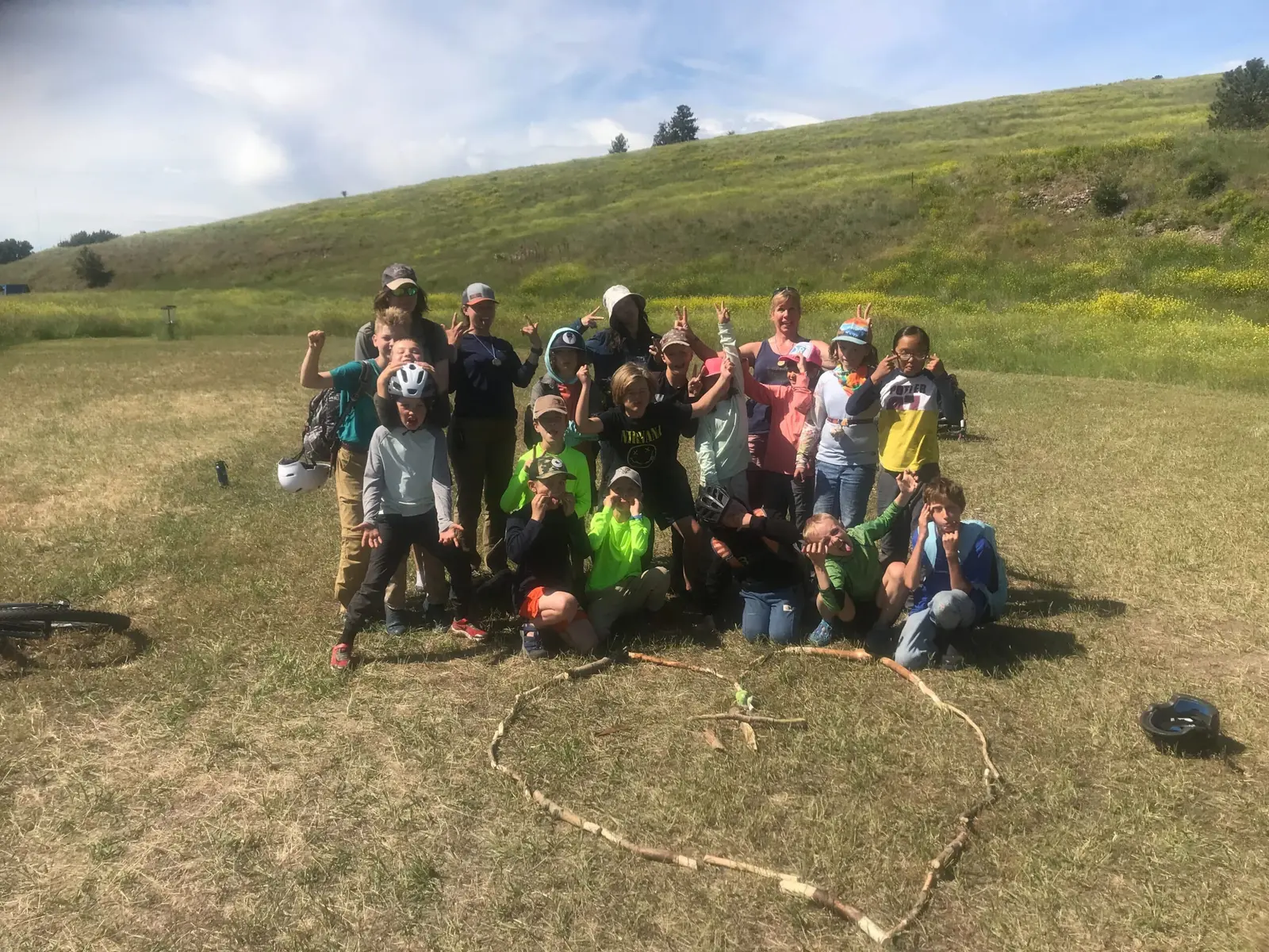 A large group of children and adults pose for a photo in an open, grassy field.