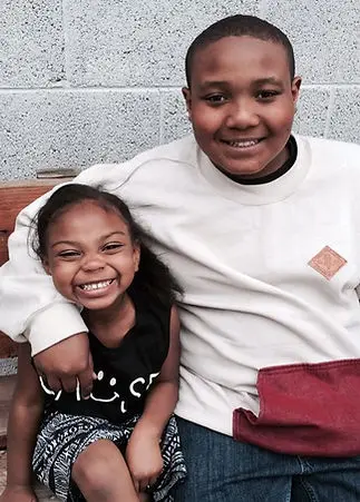 Two smiling children are sitting together.