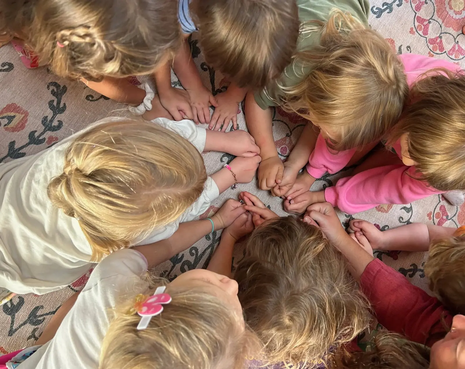 A group of children huddled together with their hands touching in the center.