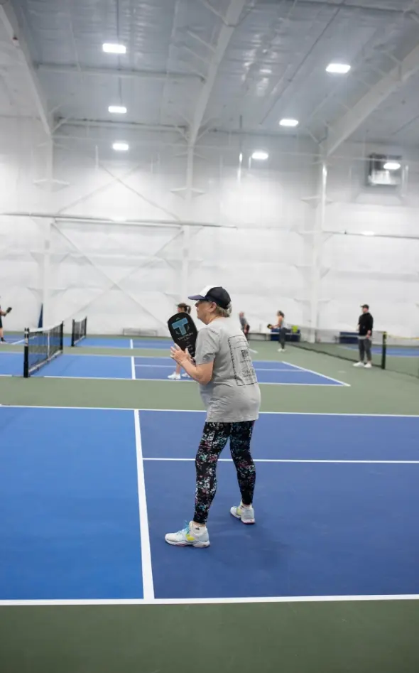 A woman plays pickleball on an indoor court.