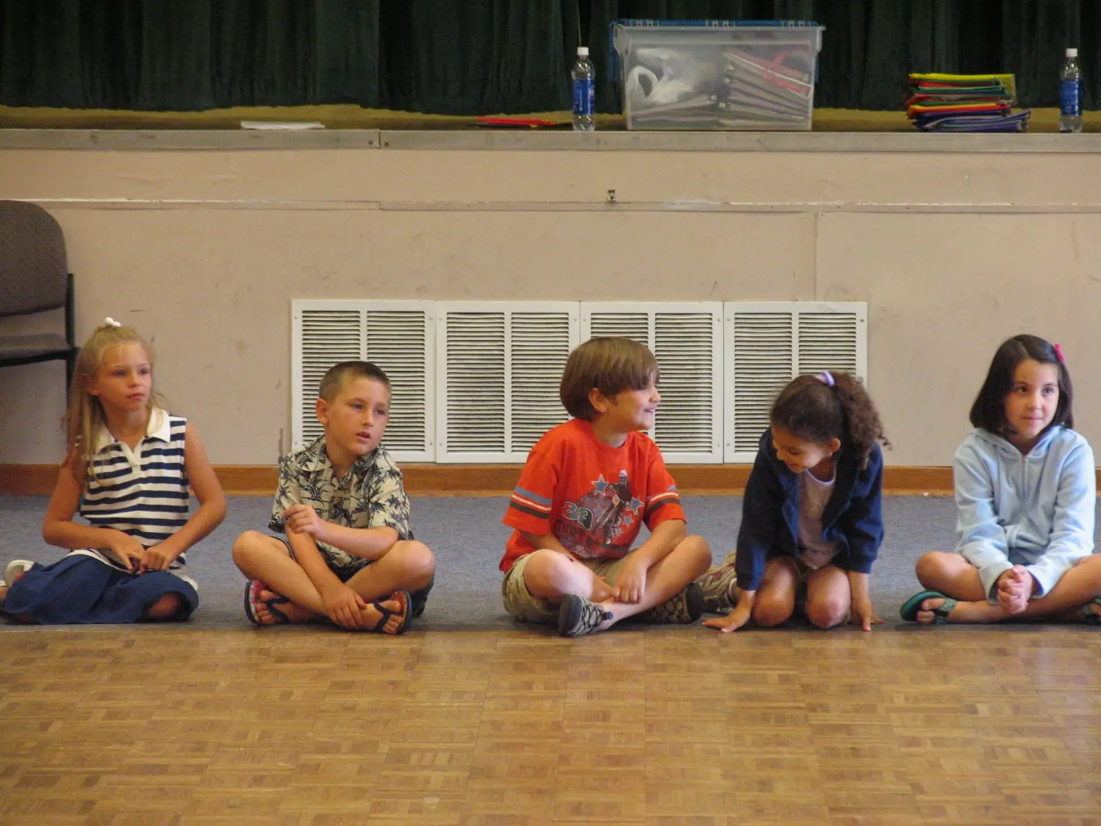 Five children sit in a row on the floor.