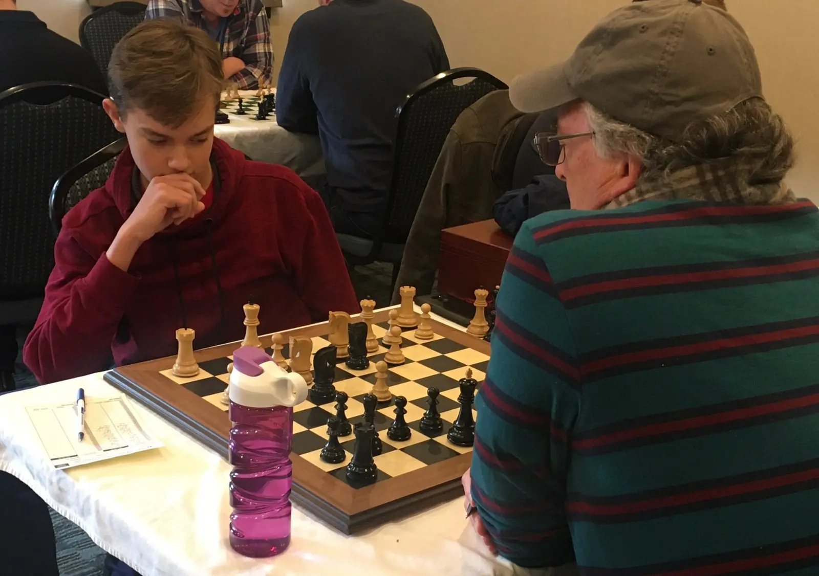 Two people are engaged in a game of chess at a table.