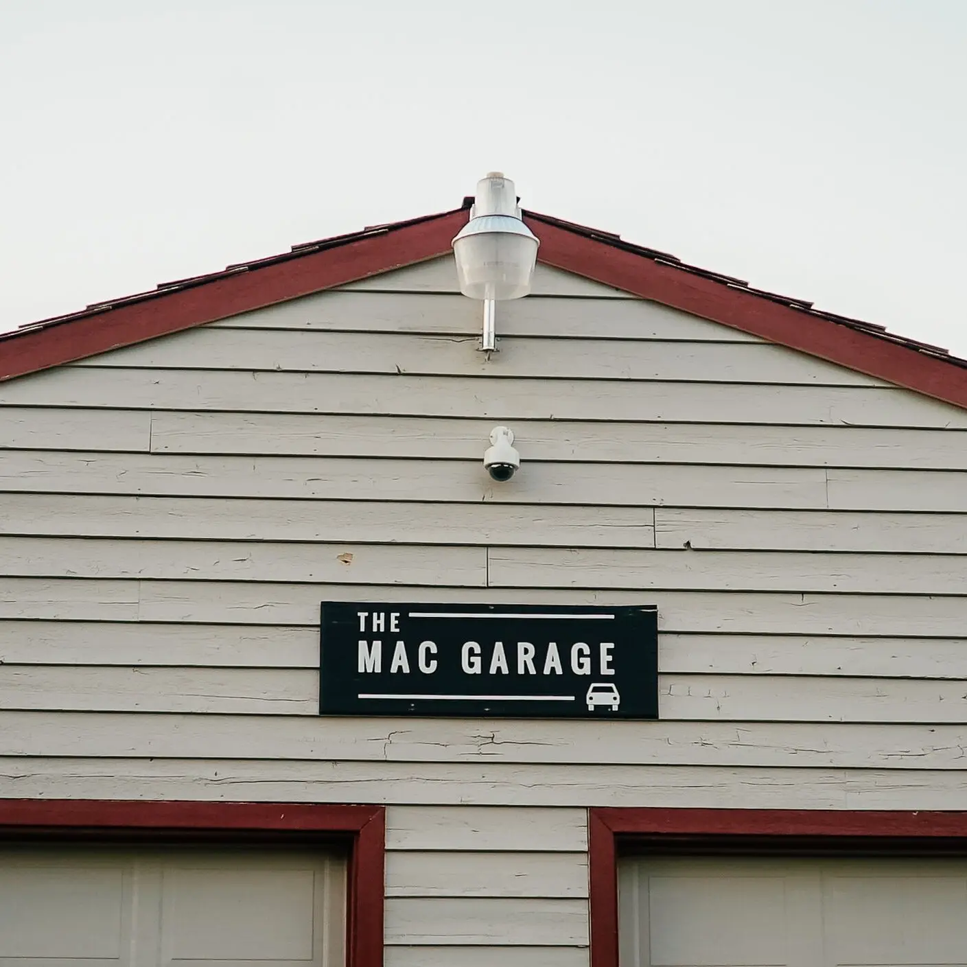 A building exterior displays a black sign with the text THE MAC GARAGE.