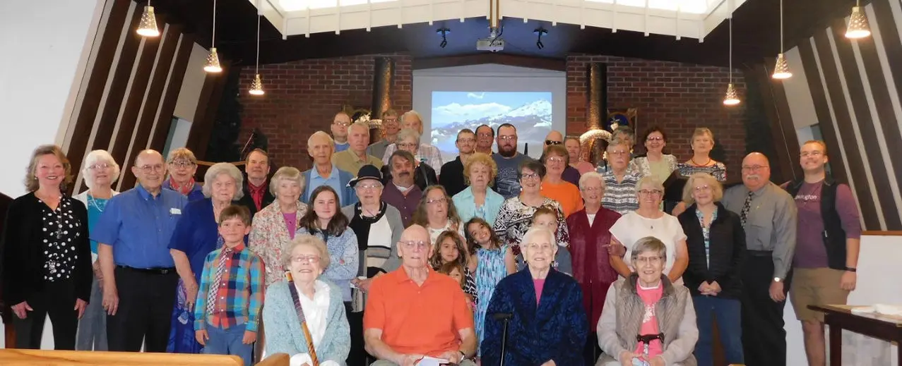 A large group of people stand together for a photo in a church sanctuary.