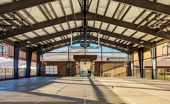A modern covered basketball court with an open-air design.
