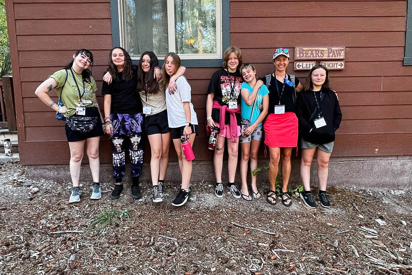 A group of young people and an instructor stand together in front of a building wall.