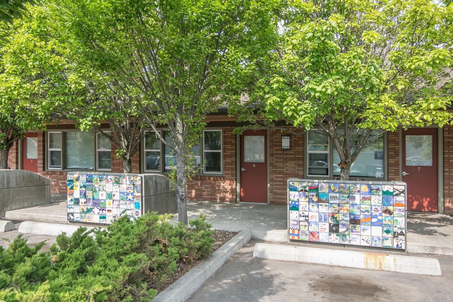 A brick building exterior features doors marked with numbers and decorative mosaic tile walls.